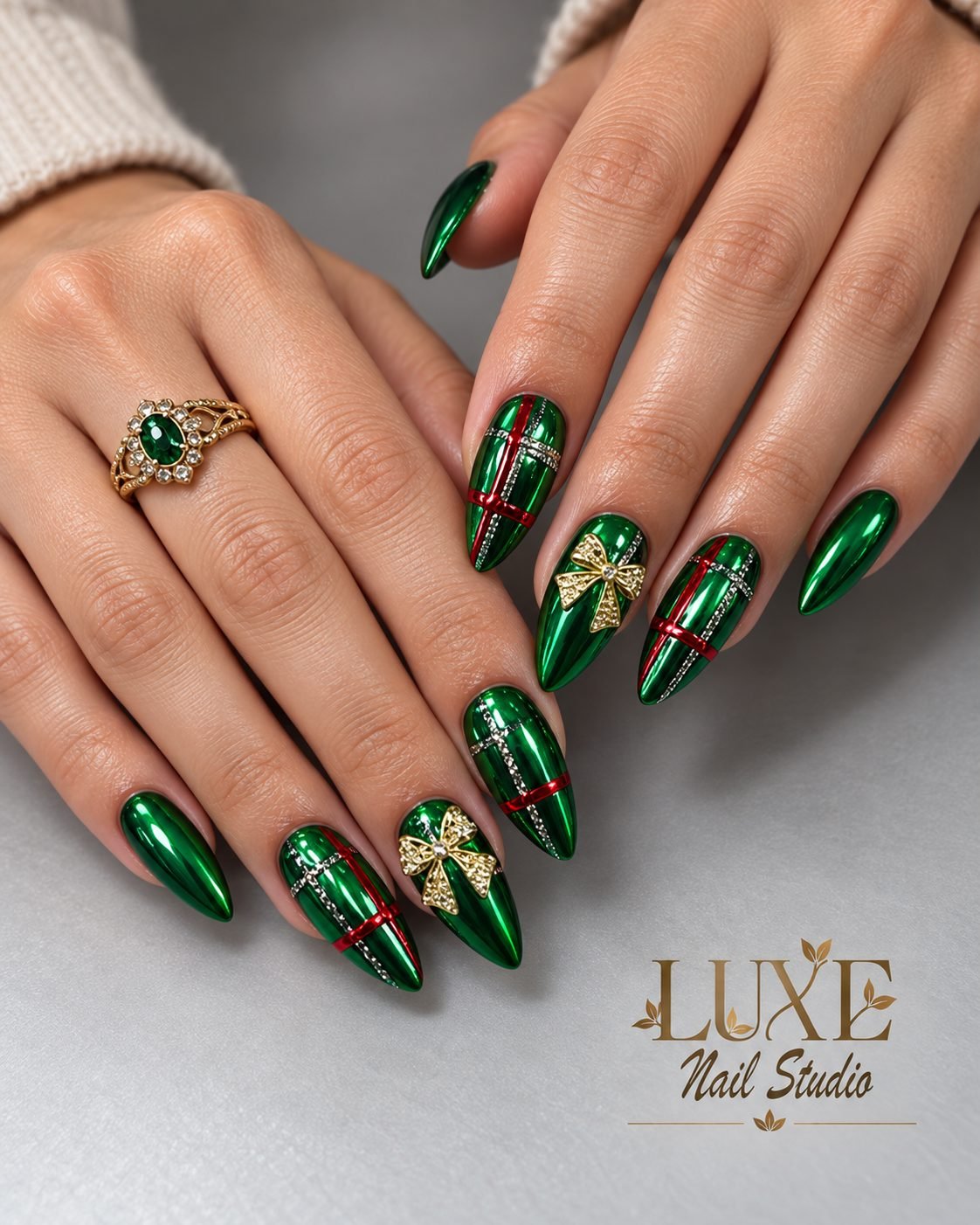 Metallic green stiletto nails with gold bows and red ribbon by Luxe Nail Studio